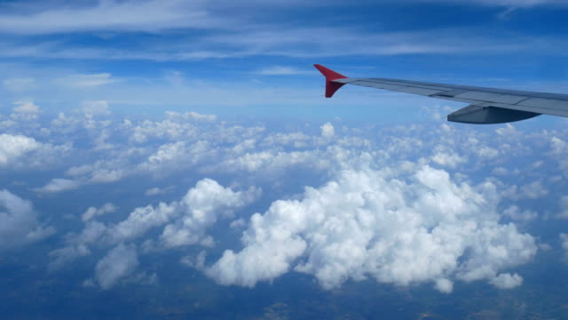 Imágenes-de-4K.-viajando-por-el-aire.-vista-aérea-a-través-de-una-ventana-del-avión.-avión-de-ala-y-hermosas-nubes-blancas-en-el-cielo-azul-de-fondo