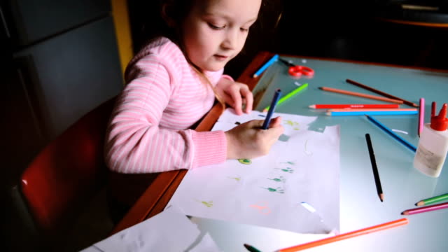 High-angle-camera-sliding-right-over-little-Caucasian-girl-child-in-pink-sweater-drawing-with-colorful-pencils-at-table