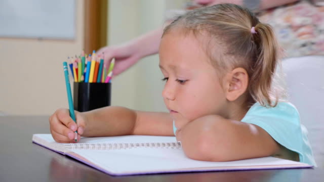 Kleine-süße-Mädchen-sitzt-im-Klassenzimmer-und-im-Heft-zu-schreiben