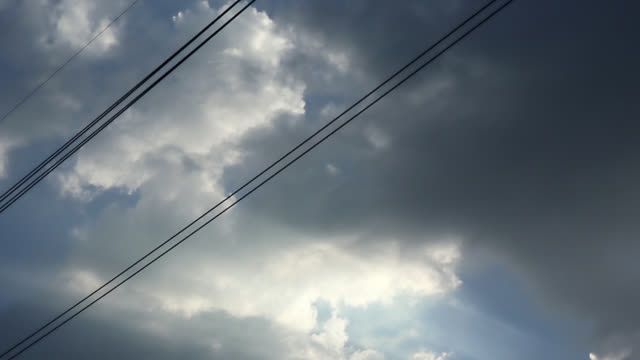 Gray-overcast-clouds-on-blue-sky-before-rain-or-storm.-Electrical-power-lines-pass-through-the-sky.