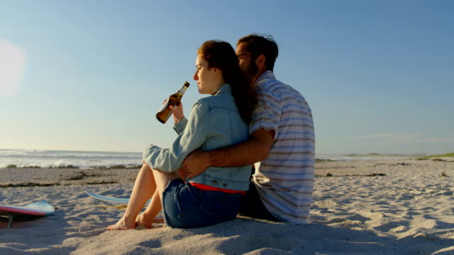 Couple-having-beer-at-beach-on-a-sunny-day-4k