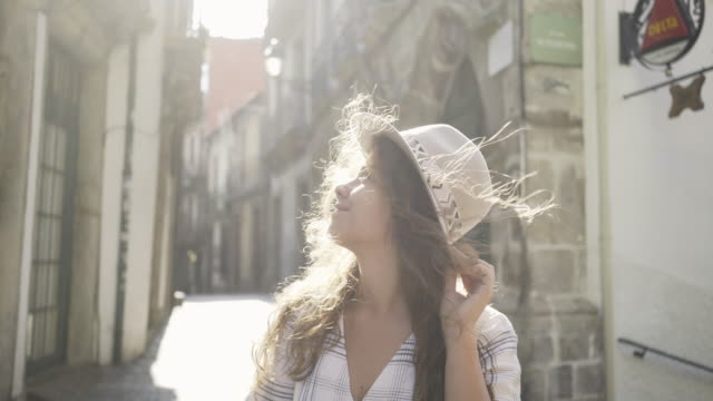 Attraktive-Frau-mit-Hut-hält-Haare-auf-Straße