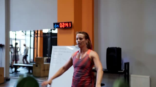 Mujer-fuerte-hace-ejercicio-de-levantamiento-de-pesas-durante-Cruz-entrenamiento-en-gimnasio