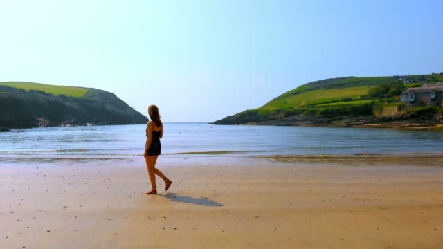 Woman-walking-on-the-beach-on-a-breezy-day-4k