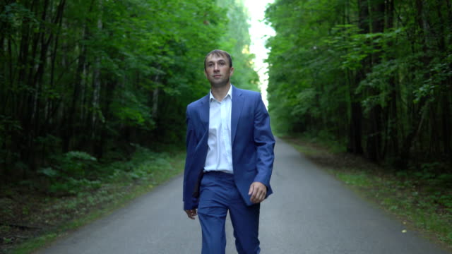 man-in-a-blue-suit-is-walking-along-the-road