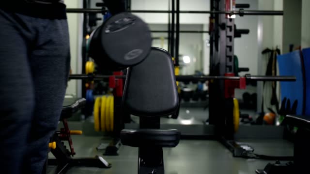 The-athlete-with-dumbbells-sits-on-a-bench,-does-an-exercise-for-two-hands-4K-Slow-Mo