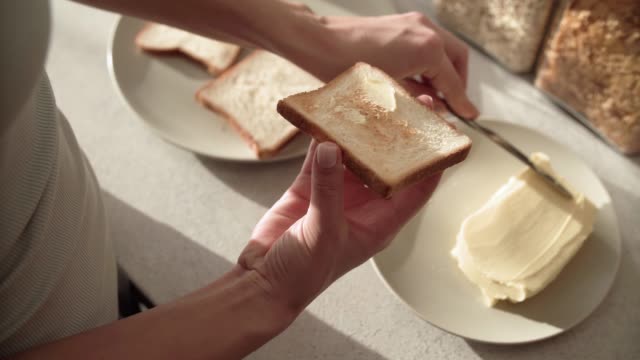 Toast-mit-Butter.-Hände,-die-Anwendung-von-Butter-auf-Brot-Closeup
