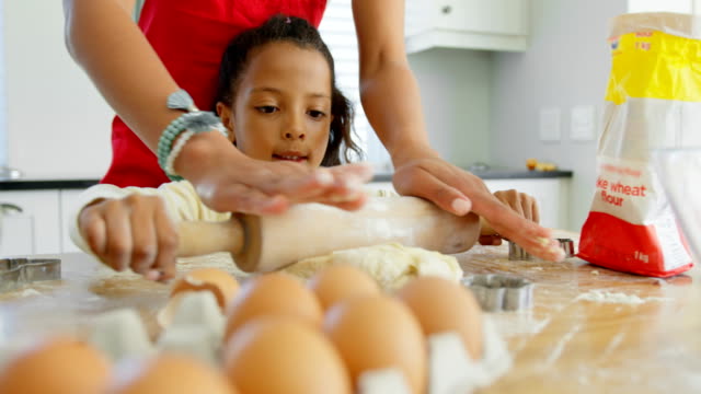 Black-mother-and-daughter-rolling-dough-with-rolling-pin-at-home-4k