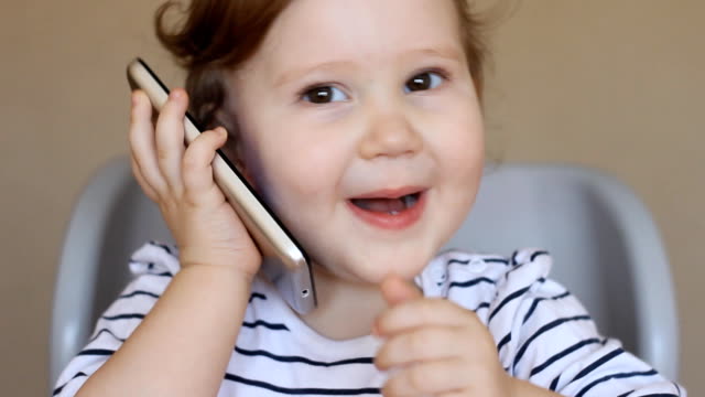 Baby-girl-talking-on-the-phone,-surprised-and-laughing