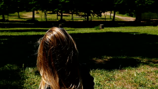 Traurige-nachdenkliche-blonde-Frau-sitzen-auf-dem-Rasen-im-Stadtpark