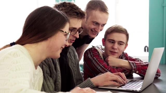 Group-of-students-talking-and-looking-at-laptop-screen