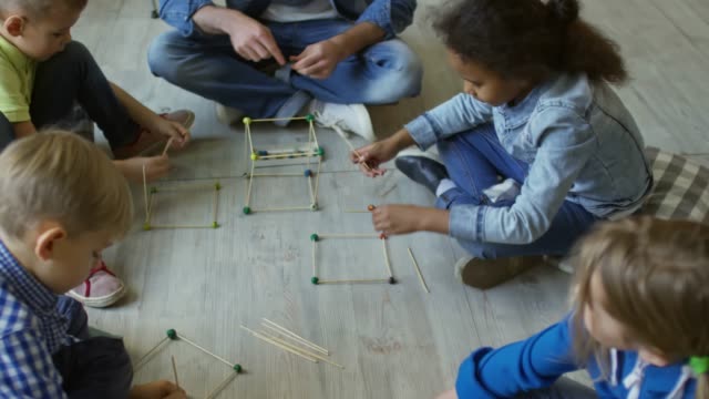 Preschool-Kids-Making-Wooden-Cubes-with-Male-Teacher