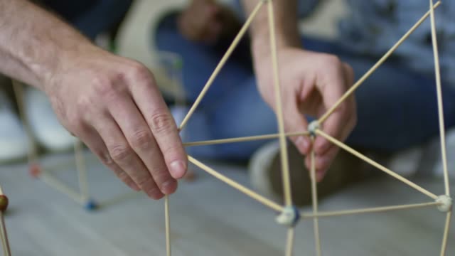Male-Hands-Making-Construction-with-Wooden-Sticks
