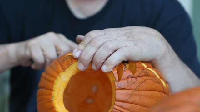 Man-carving-complex-design-on-Halloween-pumpkin