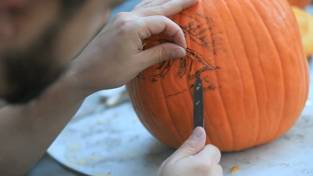 Man-using-knife-to-carve-Halloween-pumpkin