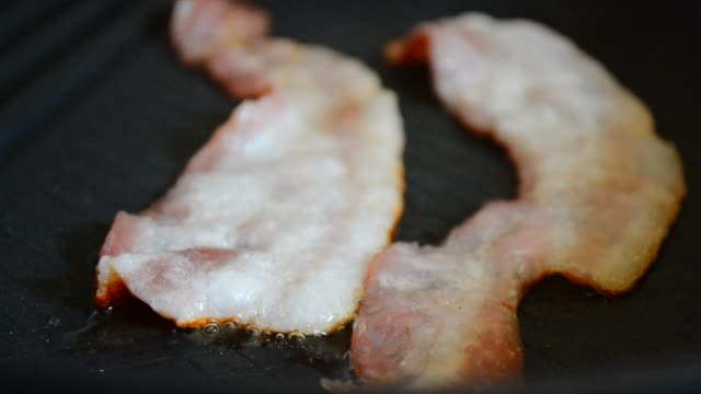 Close-up-of-a-slice-of-bacon-fried-on-a-hot-grill.