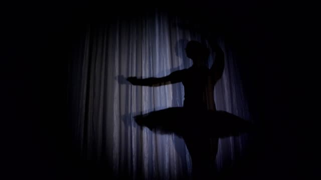 en-el-escenario-de-la-antigua-sala-de-teatro-hay-una-bailarina-danza-tutú-de-ballet,-en-rayos-de-luz,-sombra.-ella-está-bailando-con-elegancia-cierto-movimiento-de-ballet,-lago-de-los-cisnes