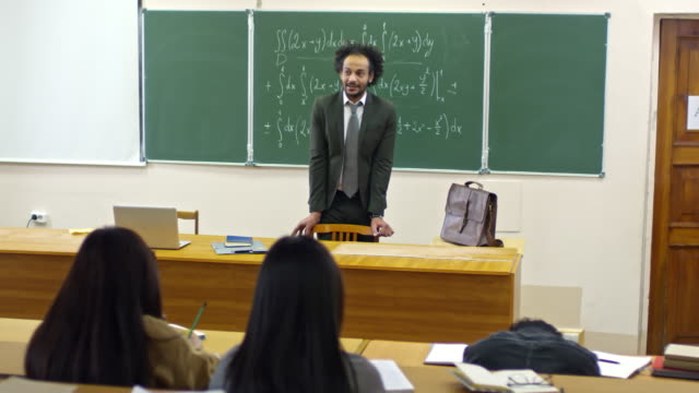 Teacher-of-Mathematics-Standing-at-Blackboard-during-Lecture