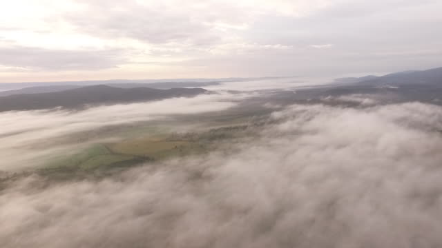 Low-clouds-and-fog-cover-Australian-farm-in-early-morning,-drone