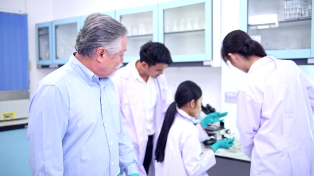 Wissenschaftler-arbeiten-im-Labor-Portrait.-Chinesischen-männlichen-wissenschaftlicher-Arbeiten-im-Labor-Portrait-mit-seinem-Team-im-Hintergrund.