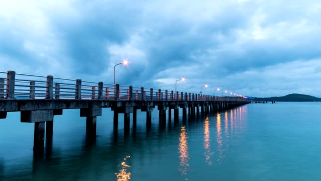 Timelapse-clouds-moving-fast-in-sunrise-or-sunset-over-sea-with-cement-bridge-is-in-the-foreground