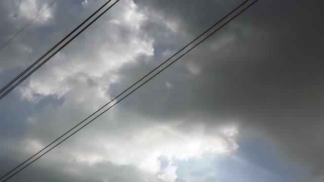 Gray-overcast-clouds-on-blue-sky-before-rain-or-storm.-Electrical-power-lines-pass-through-the-sky.
