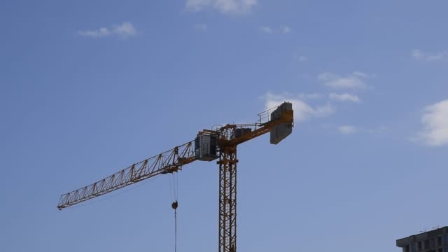 Tower-building-crane-against-the-blue-sky-and-sun.-Construction-of-new-buildings-with-a-crane.-Tower-crane.