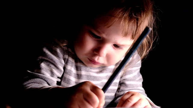 Little-girl-diligently-draws-a-pencil-on-a-piece-of-paper,-slow-motion