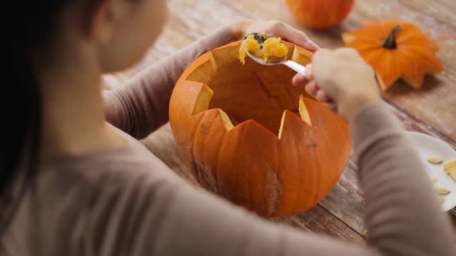 close-up-of-woman-carving-halloween-pumpkin