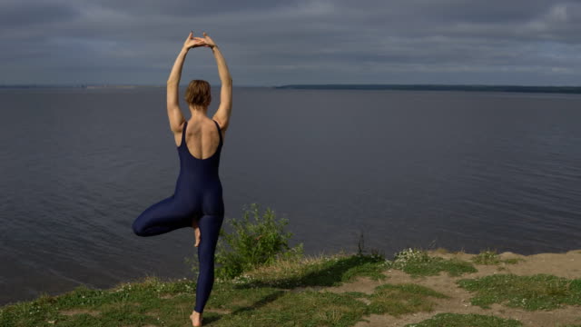 Yoga-woman-in-sportswear-pose-against-lake