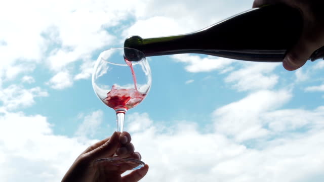 Wine-is-poured-into-a-glass-against-the-sky.