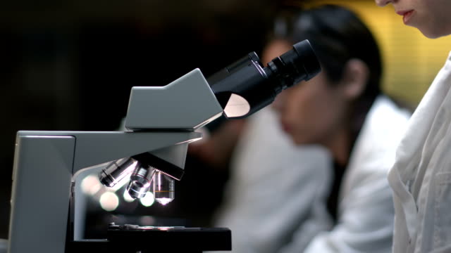 College-Students-in-a-lab-look-through-a-microscope-during-their-experiment