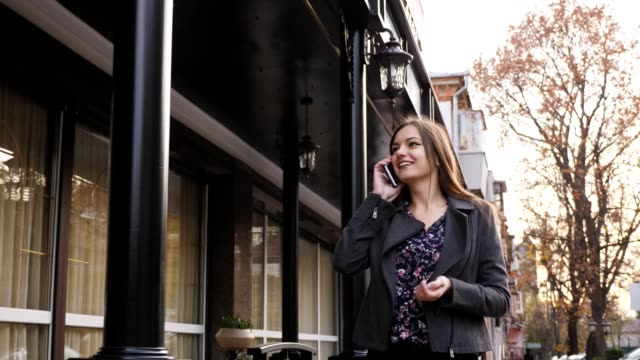Attractive-caucasian-businesswoman-walking-on-the-street-on-the-office-building-background,-talking-on-the-phone.