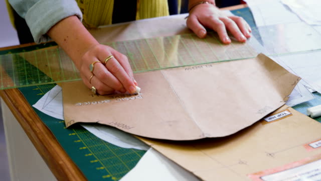 Fashion-designer-marking-on-brown-paper-at-desk-4k