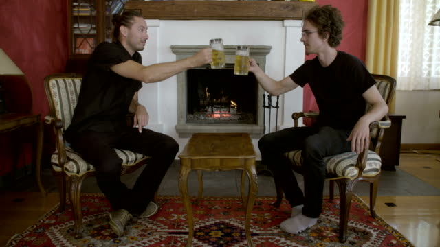 Two-men-drinking-beer-in-front-of-the-fireplace