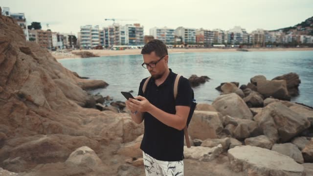 Hombre-en-una-orilla-del-mar-con-un-smartphone.