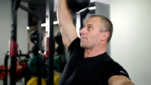 Close-up.-Handsome-guy-doing-exercise-with-a-kettlebell-in-the-gym-4K-Slow-Mo