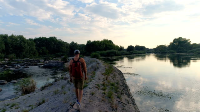 Hombre-joven-caminando-por-la-orilla-del-río