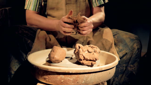 Potters-hands-work-on-several-large-lumps-of-crude-clay.