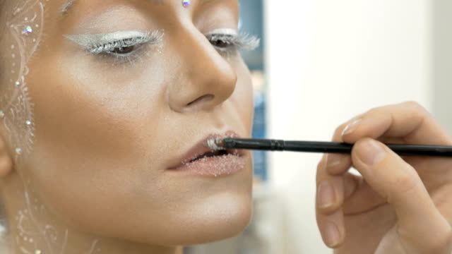 El-artista-de-maquillaje-pinta-labios-de-la-modelo,-con-un-cepillo-especial.-Close-up