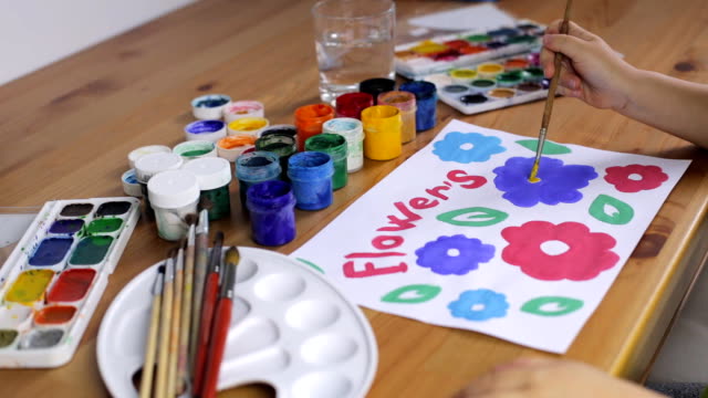 Child's-hand-paints-colorful-flowers