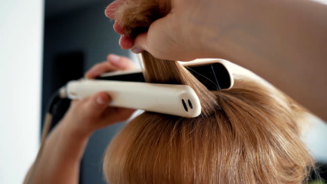 junge-Frau-richten-Sie-ihr-Haar-mit-Haar-Haarglätter-Nahaufnahme