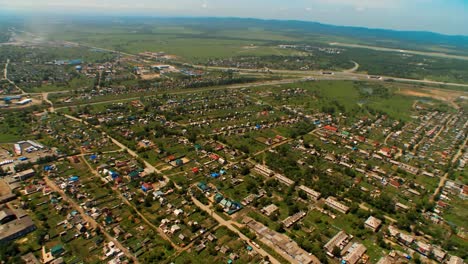 Helicopter-(-drone,-quadcopter-)-flies-over-a-settlement,-trees-and-fields