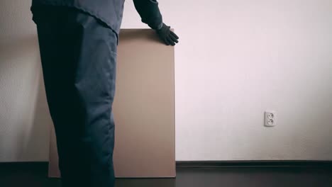 der-Möbel-Sammler-stellt-eine-Kiste-mit-Möbel-in-der-Nähe-der-Wand