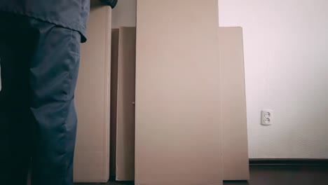 der-Möbel-Sammler-stellt-die-vierte-Box-mit-Möbeln-in-der-Nähe-der-Wand