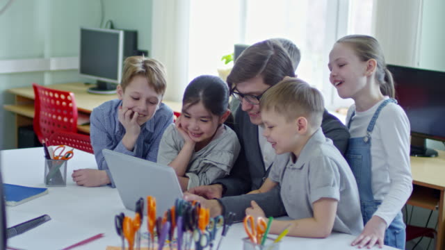 Niños-que-utilizan-ordenador-portátil-con-el-maestro