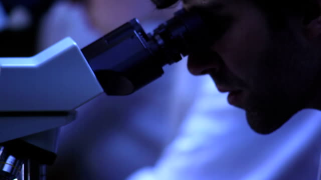 Close-up-of-a-researcher-looking-into-a-microscope-in-the-lab