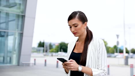 Beautiful-Business-Woman-Using-Phone-While-Walking-Near-Office