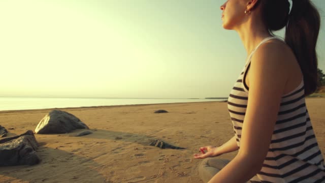 Aktive-junge-Frau-Stretching-und-Yoga-am-Strand-bei-Sonnenuntergang-zu-praktizieren.
