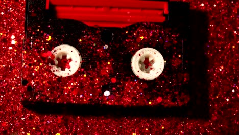 Black-video-cassette-on-the-background-of-red-glitter